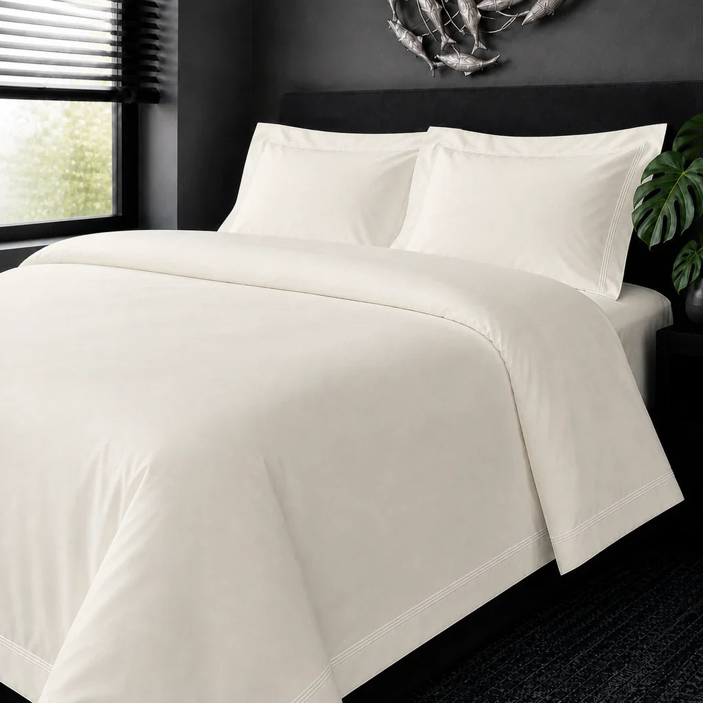 Cream cotton 200TC Oxford duvet cover set with white two-row satin stitch – on-bed view | Linen & Co
