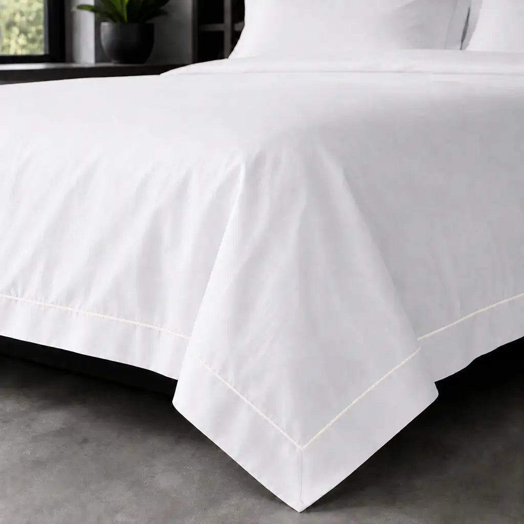 White polycotton percale Oxford duvet cover set with cream one-row satin stitch – on-bed view | Linen & Co