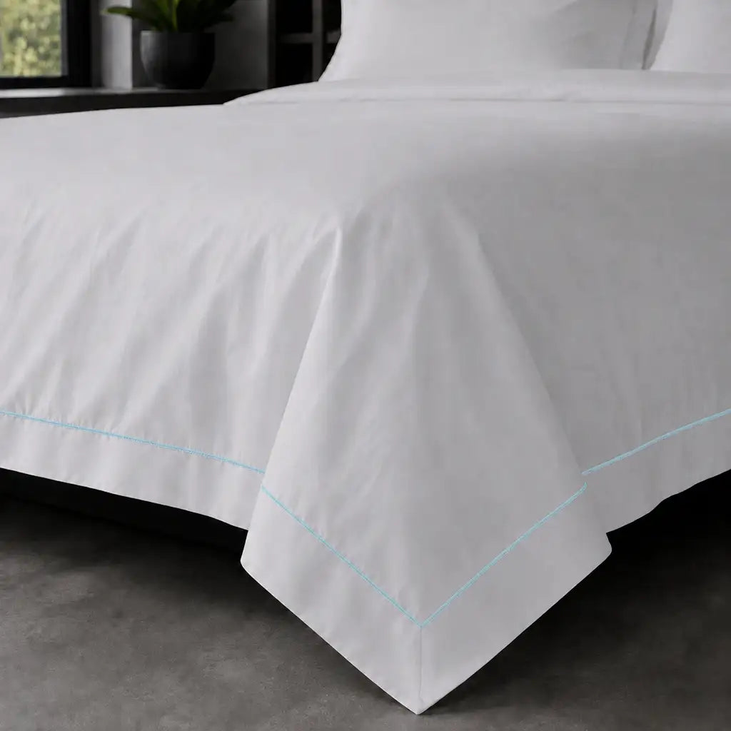 White polycotton percale Oxford duvet cover set with duck egg one-row satin stitch – on-bed view | Linen & Co