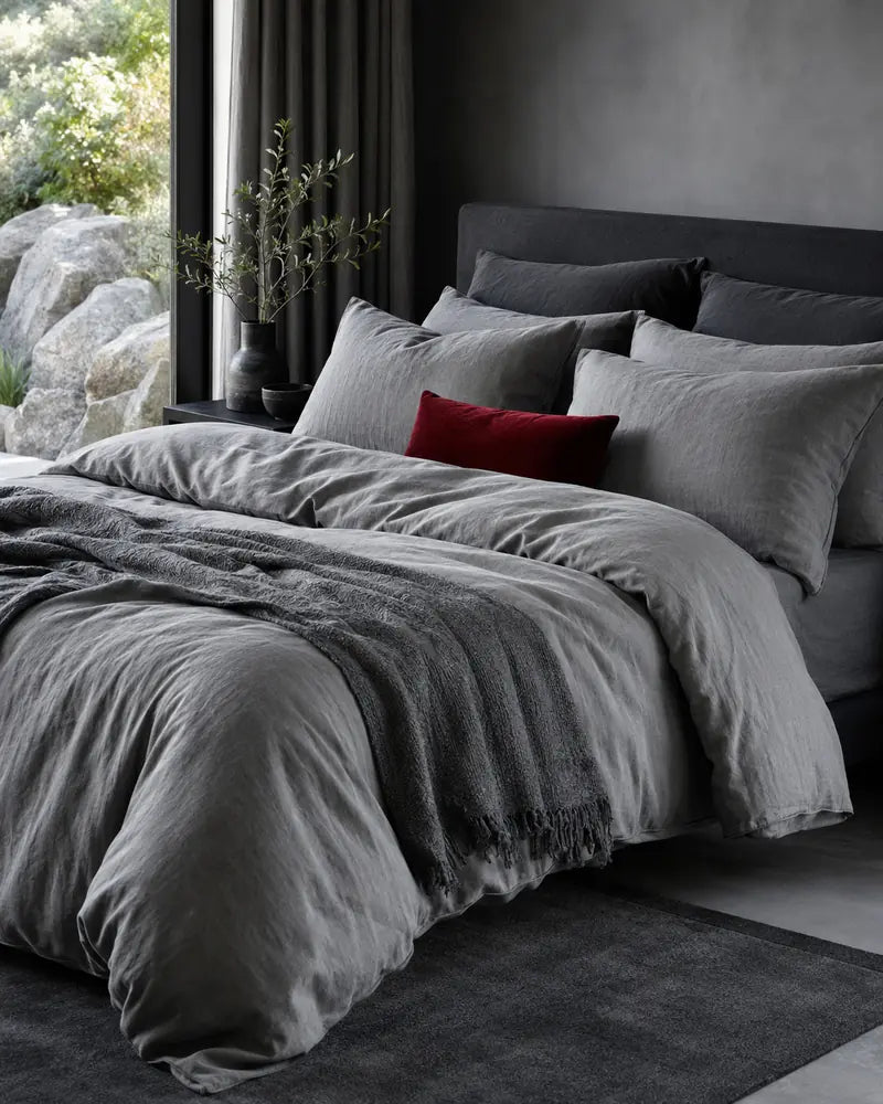 Grey bed linen with a deep red accent cushion
