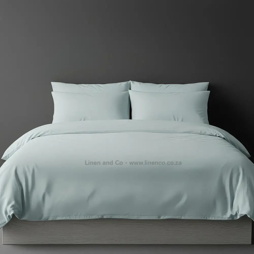 Duck Egg  percale duvet cover set from Linen and Co, showcasing pristine white bedding against a dark grey background, demonstrating clean and professional hospitality textile design
