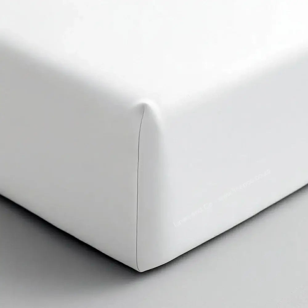 White fitted sheet corner on mattress showing elastic edge and smooth percale fabric - Linen & Co hospitality bedding