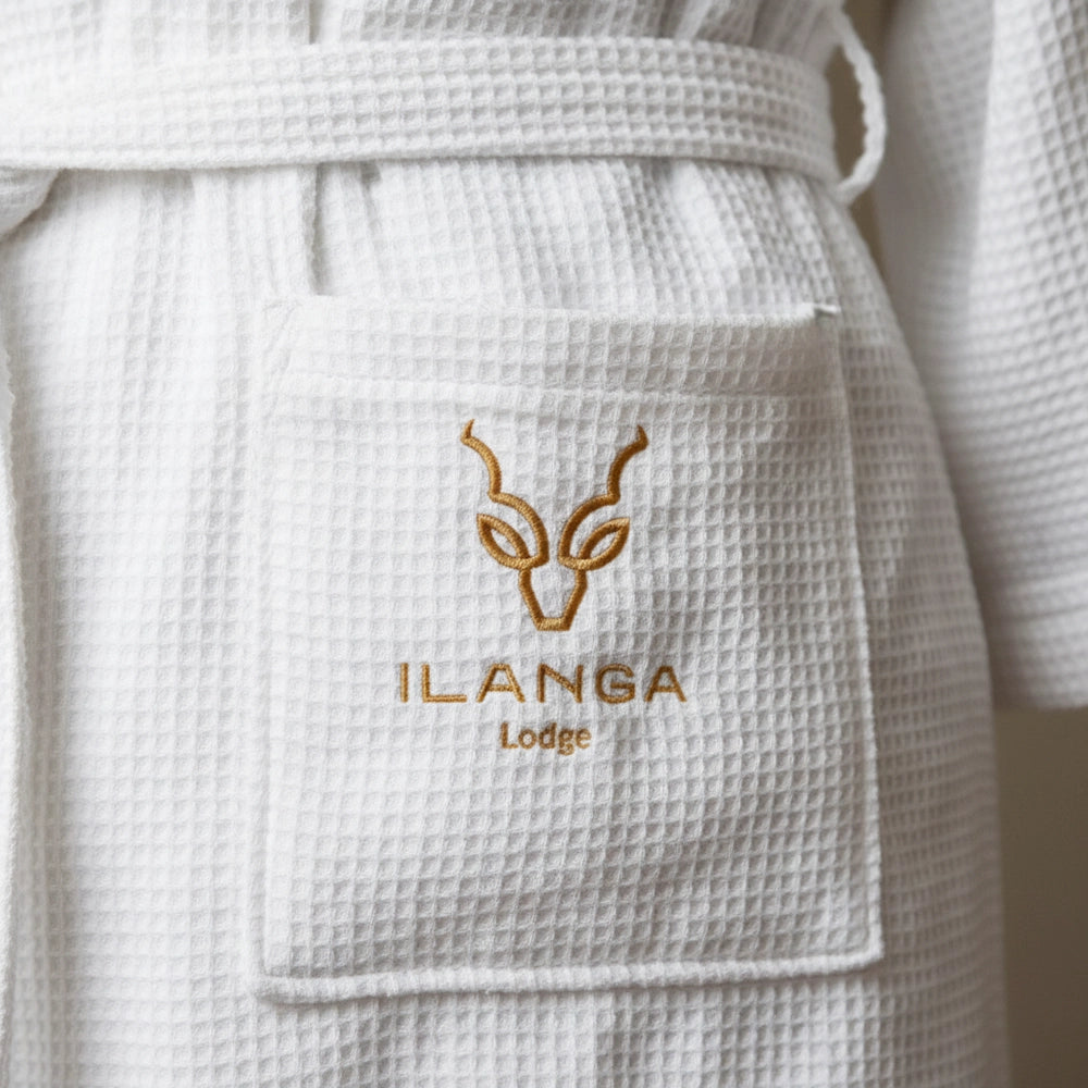 Custom embroidered logo on white waffle weave gown by Linen and Co - premium hospitality towel branding detail