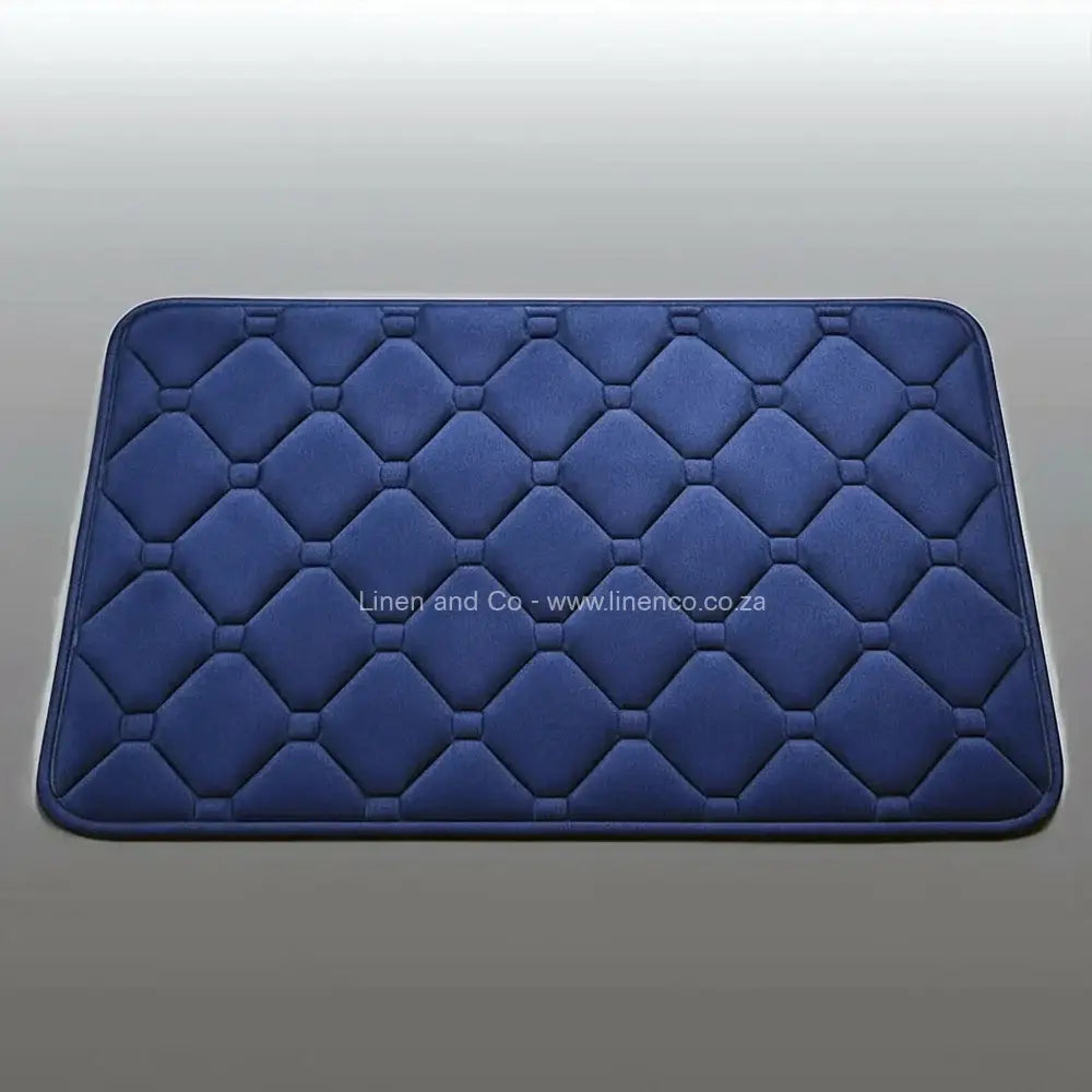 Navy memory foam bath mat by Linen & Co on soft grey gradient background, 50x80cm luxury microfibre bathroom accessory with non-slip backing