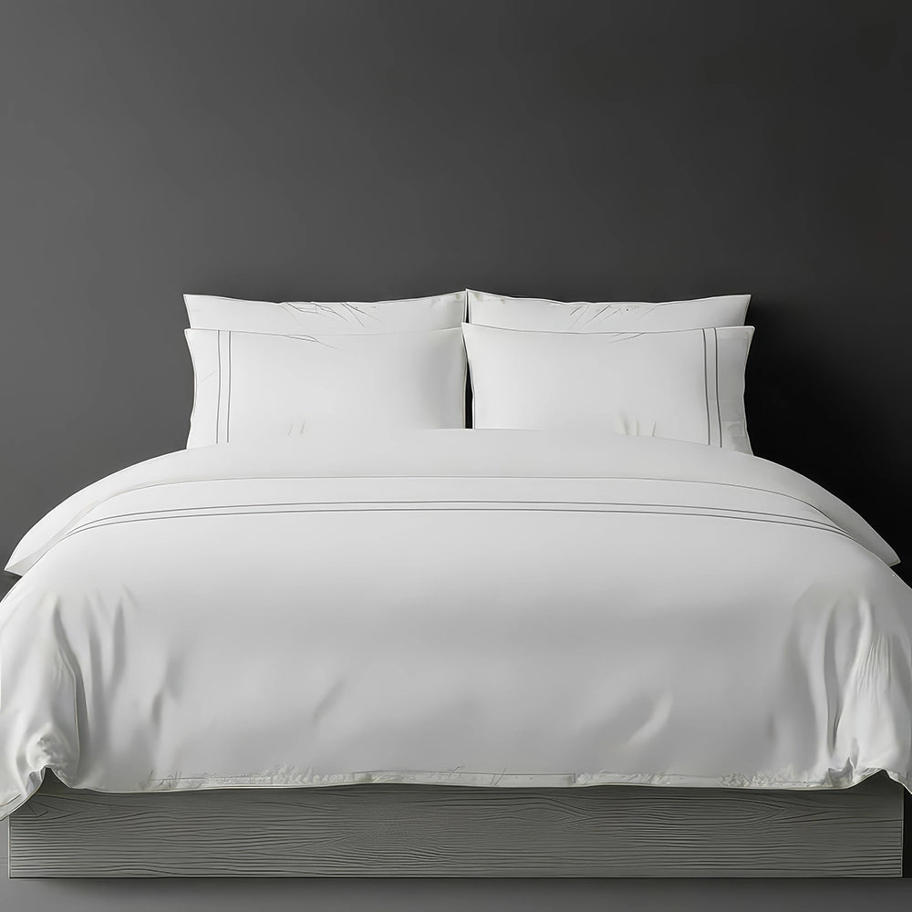White percale duvet cover set with two-row white satin stitch border from Linen and Co, showcasing elegant hospitality bedding with subtle decorative detailing against a dark grey background.