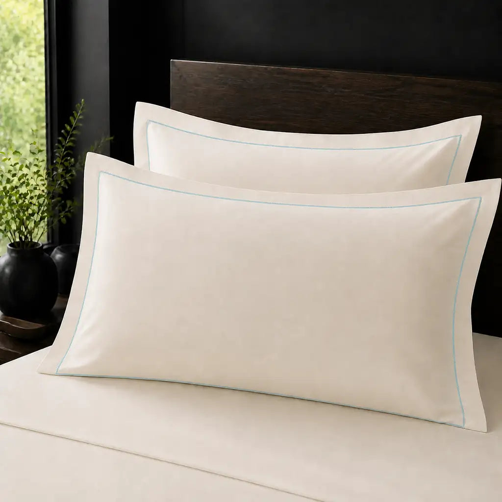 Ivory Cream 100% Cotton Percale 200TC Oxford pillow cases on a bed with Duck Egg one-row satin stitch - Linen and Co