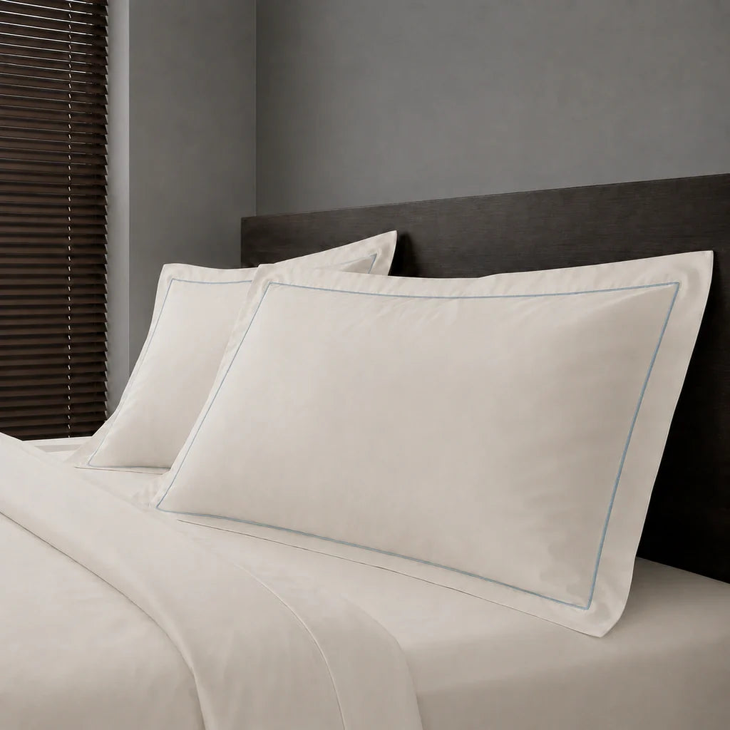 Ivory Cream Polycotton Percale 200TC Oxford pillow cases on a bed with Duck Egg one-row satin stitch - Linen and Co