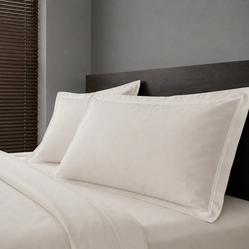 Ivory Cream Polycotton Percale 200TC Oxford pillow cases on a bed with White two-row satin stitch - Linen and Co