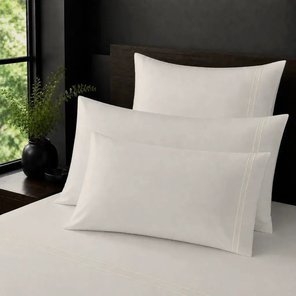 Cream Polycotton Percale 200TC plain pillow cases with Cream two-row satin stitch - on the bed - Linen and Co