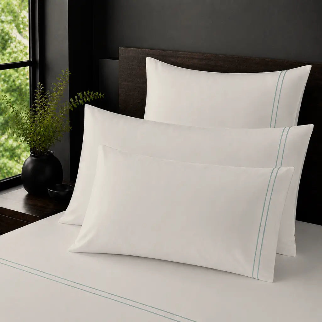Cream Polycotton Percale 200TC plain pillow cases with Duck Egg two-row satin stitch - on the bed - Linen and Co