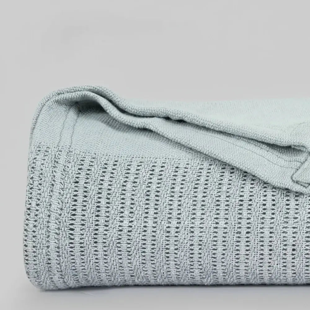 light grey cotton cellular blanket showing textured waffle weave fabric on neutral grey background—soft, breathable bedding by Linen & Co