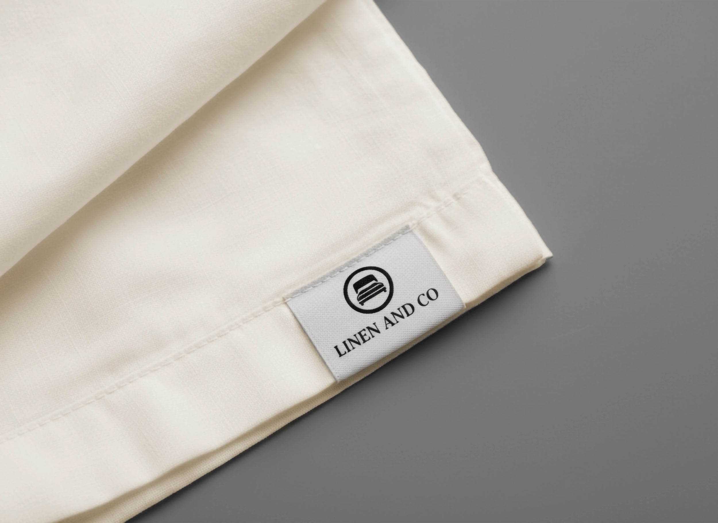 Cream linen fabric close-up with Linen and Co label by Linen and Co - premium hospitality textile branding detail