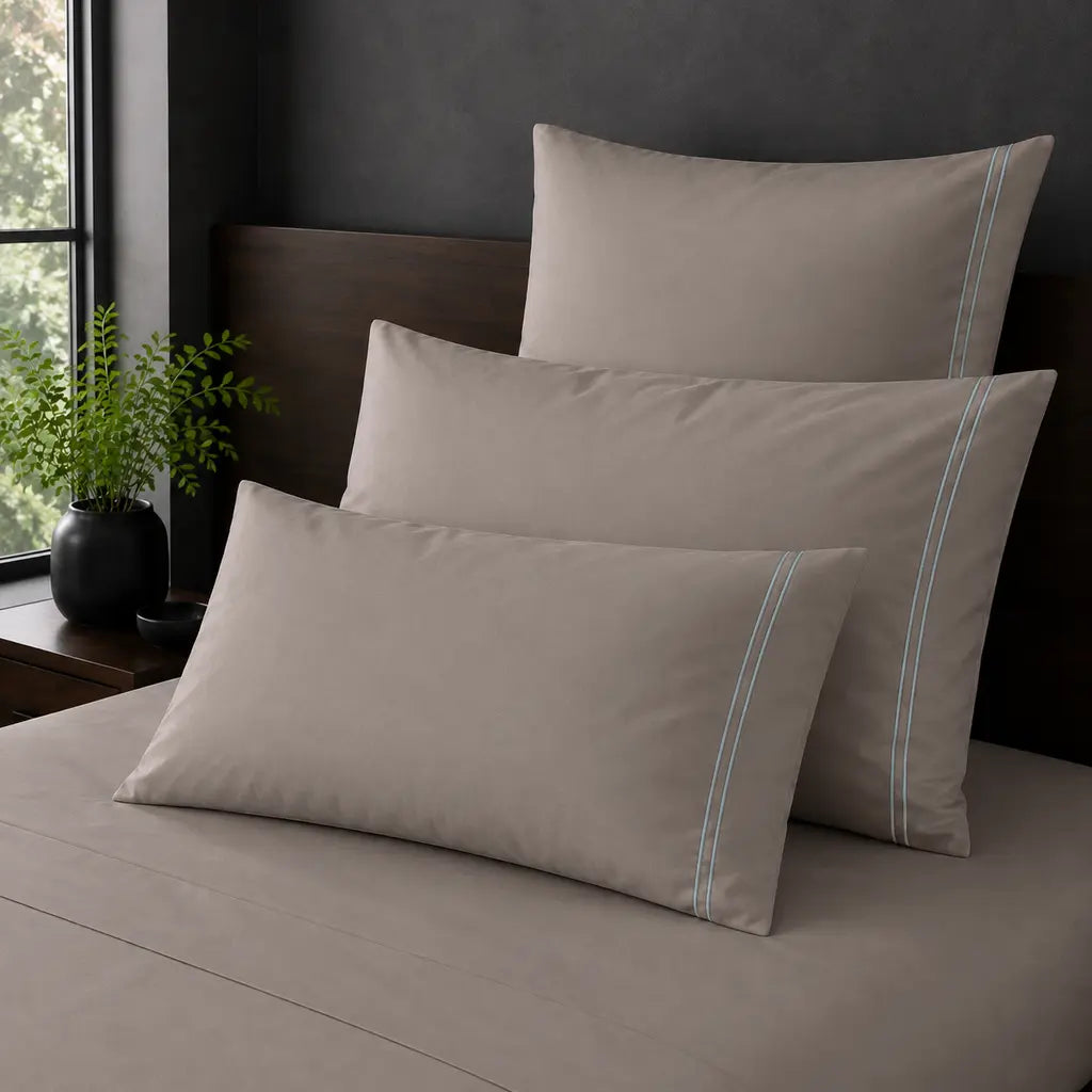 Stone Polycotton Percale 200TC Standard, King and Continental pillowcases on a bed with two row of Duck Egg satin stitch.