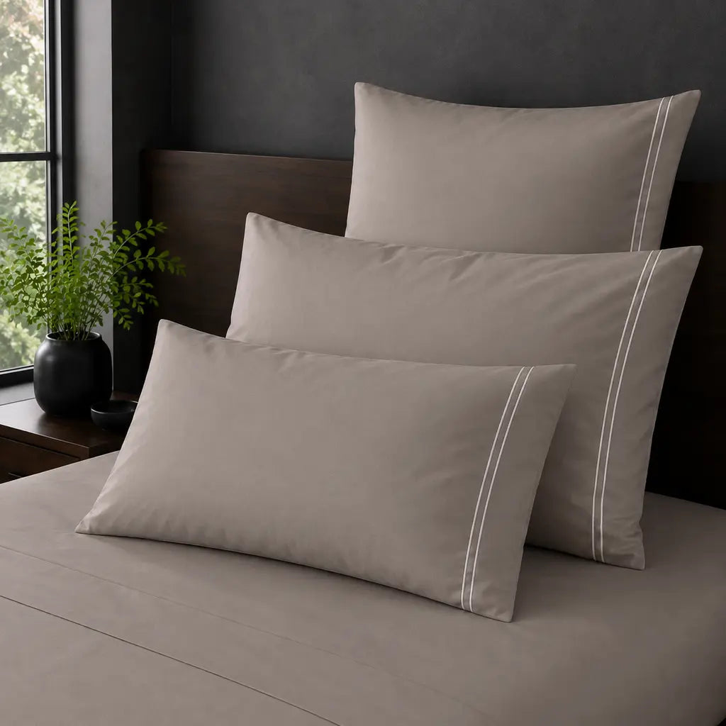Stone Polycotton Percale 200TC Standard, King and Continental pillowcases on a bed with two row White satin stitch.