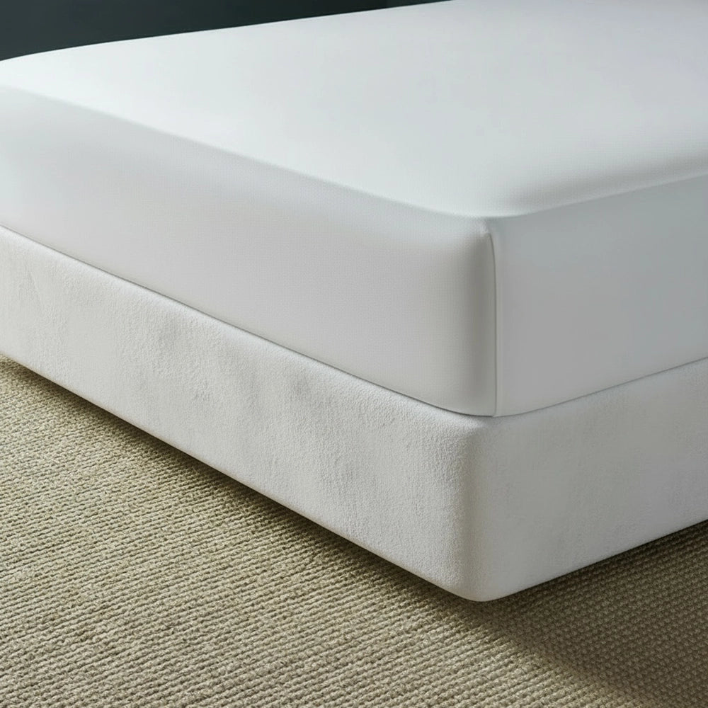 White mock suede base wrap covering bed base with white fitted sheet on beige jute mat—luxury bed base cover by Linen & Co