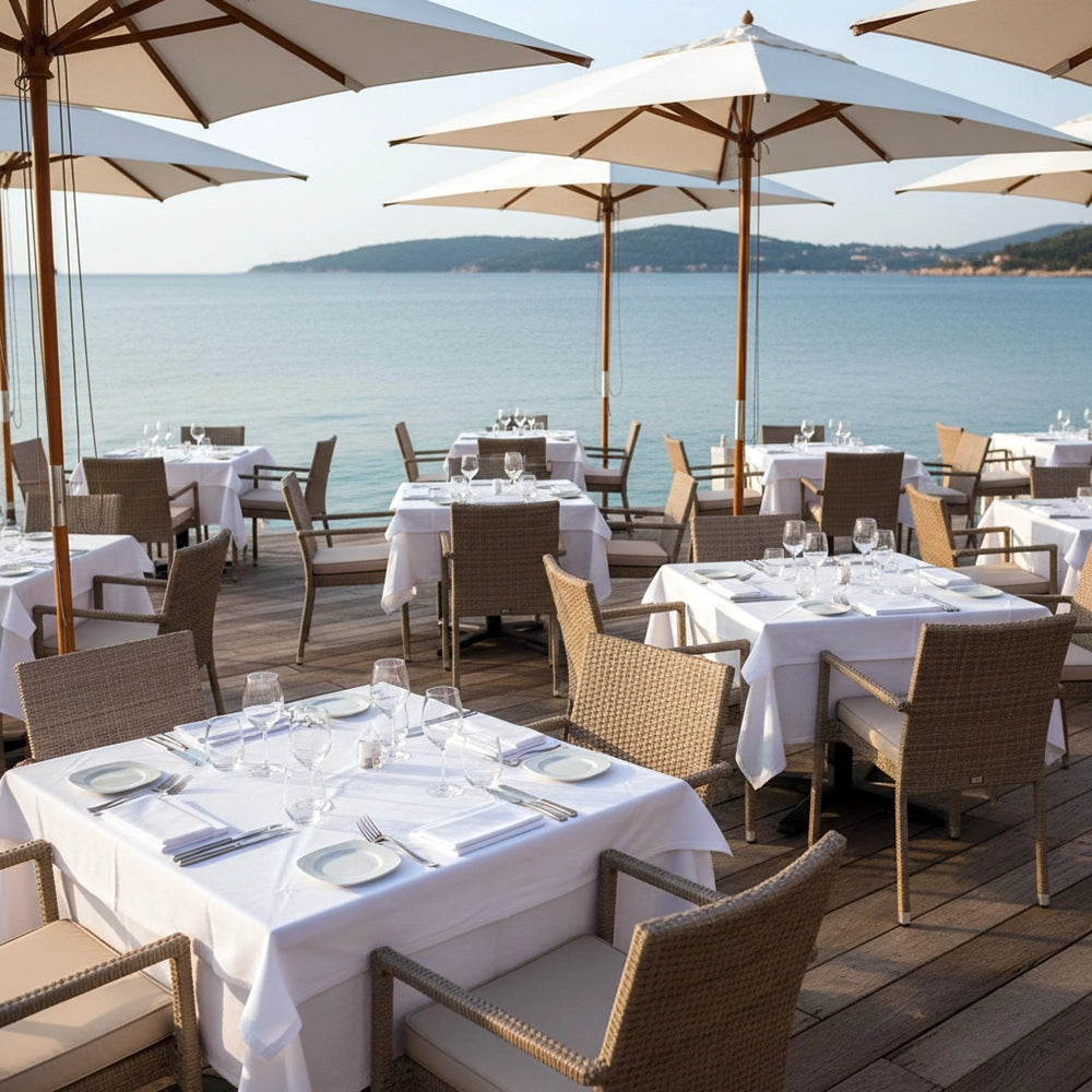 White table linen in an outdoor seaside restaurant setting by Linen and Co - Premium hospitality table linen.