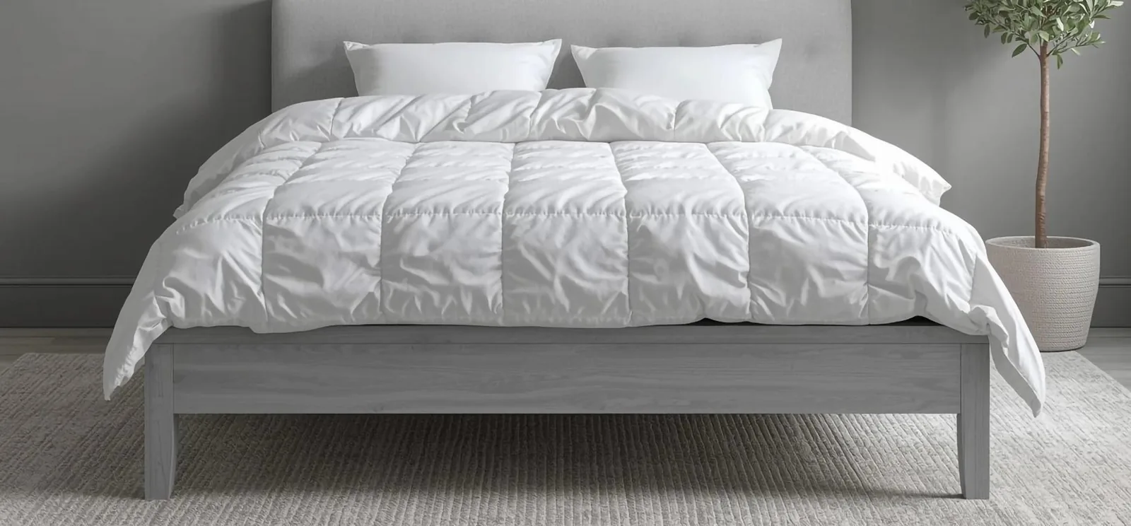 A white quilted duvet inner and pillows on a grey bed