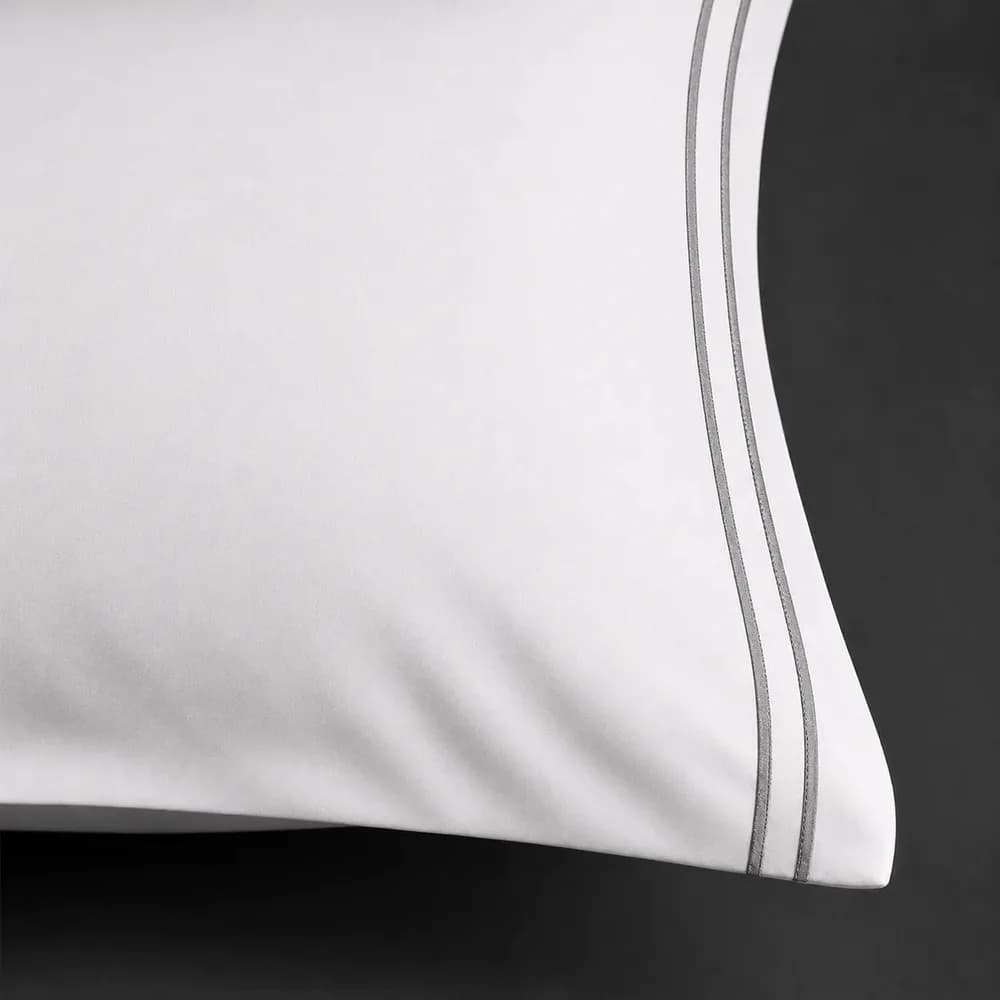 Two rows of grey satin stitch along the edge of a white percale pillowcase by Linen and Co