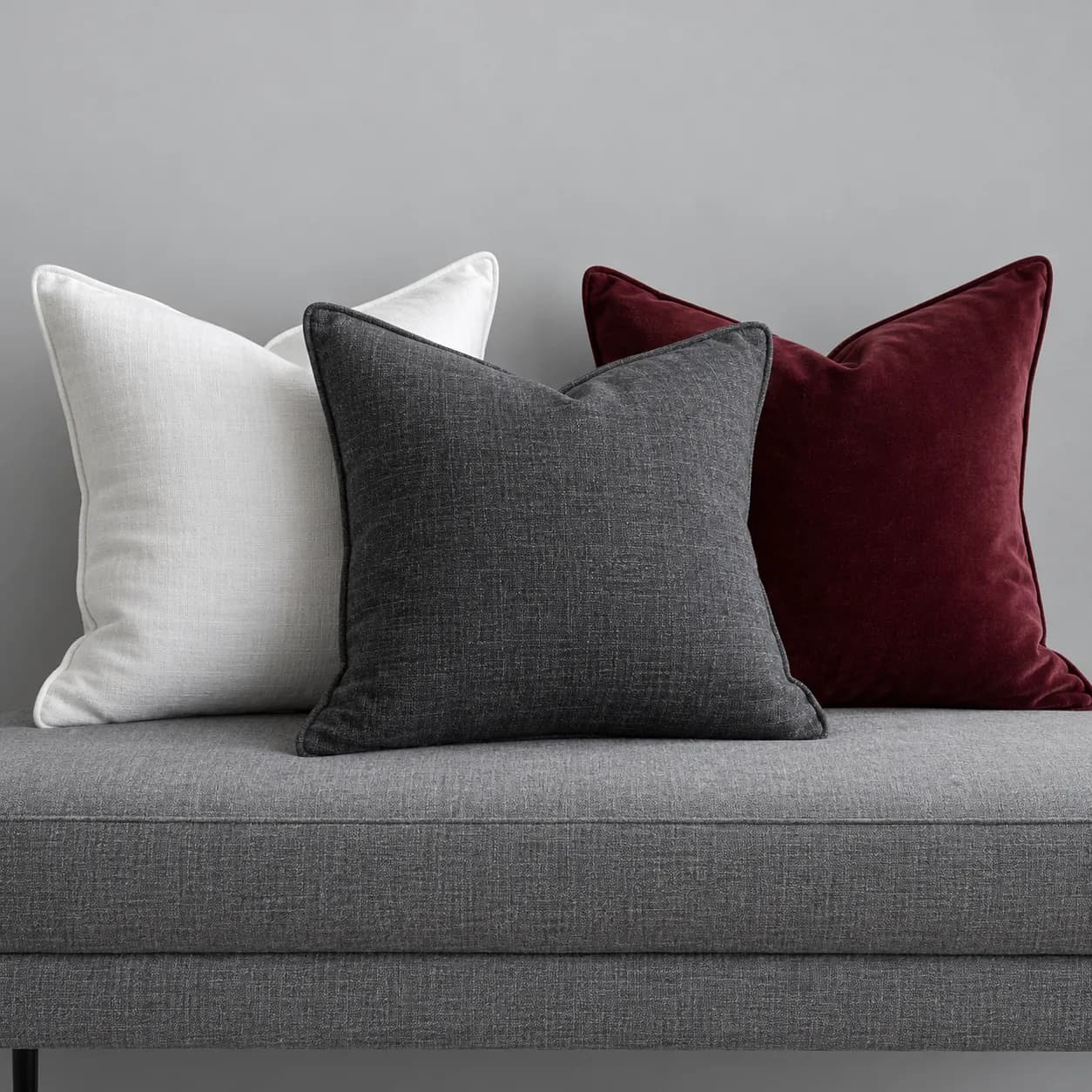 White, charcoal and burgundy scatter cushions on a grey bench