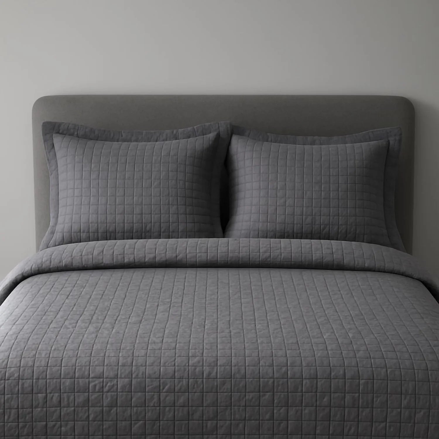 Grey Quilted Bedspread with Matching Pillows on a grey background