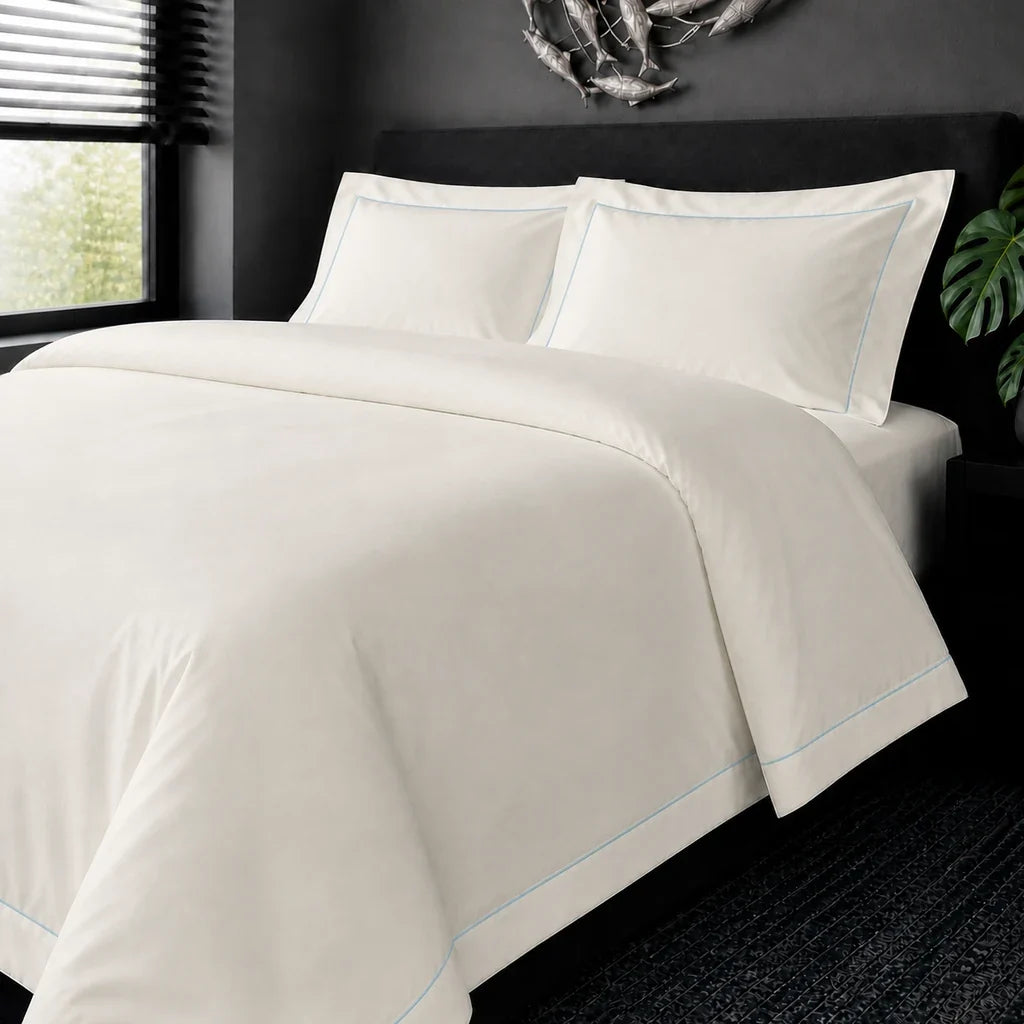 Cream cotton 200TC Oxford duvet cover set with duck egg one-row satin stitch – on-bed view | Linen & Co