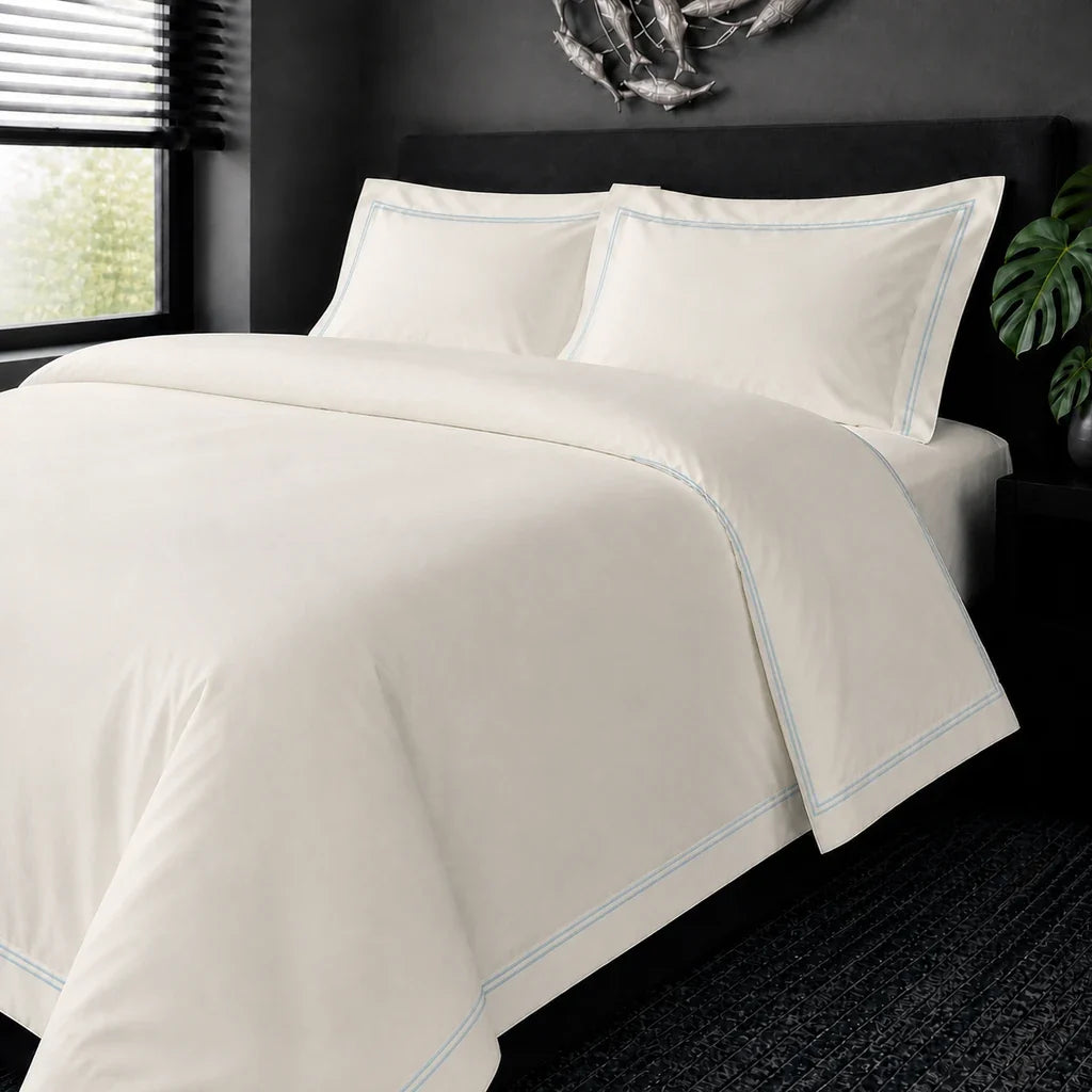 Cream cotton 200TC Oxford duvet cover set with duck egg two-row satin stitch – on-bed view | Linen & Co