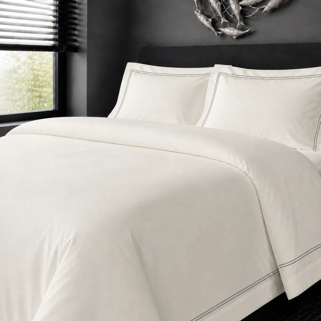 Cream cotton 200TC Oxford duvet cover set with grey two-row satin stitch – on-bed view | Linen & Co