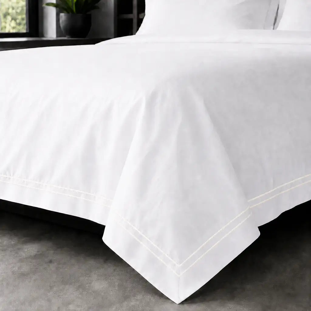 White polycotton percale Oxford duvet cover set with cream two-row satin stitch – on-bed view | Linen & Co