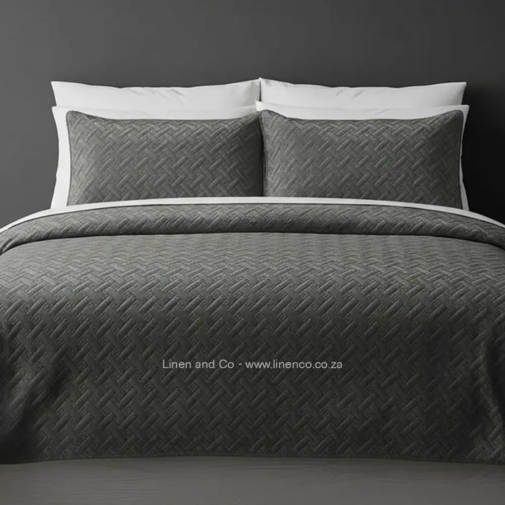 Grey Quilted Bedspread Set with Italian Velvet, showcasing textured comforter and matching pillow cases on a bed against a dark grey wall, highlighting professional hospitality textile styling by Linen and Co.