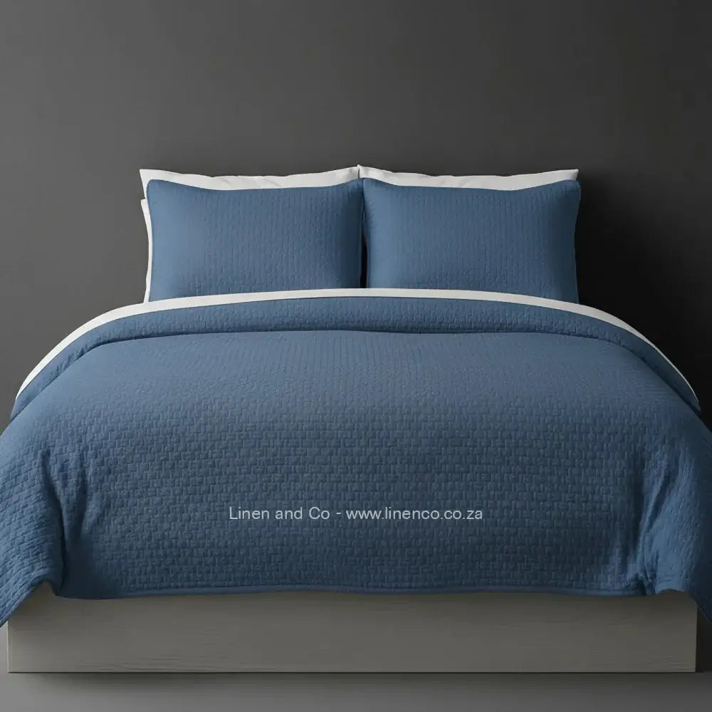 Stone Quilted Bedspread Set with Berlin Design, showcasing textured comforter and matching pillow cases on a bed against a dark grey wall, highlighting professional hospitality textile styling by Linen and Co.