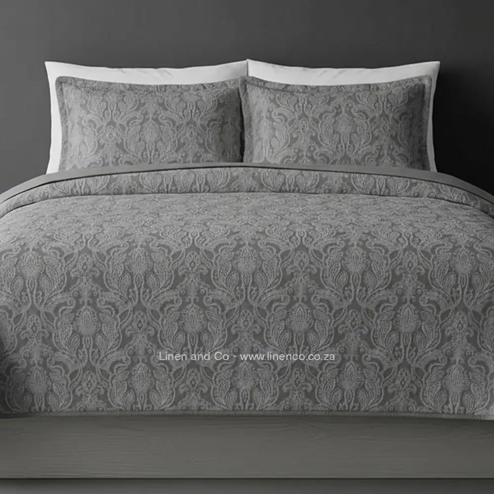  Grey Kensington Jacquard Bedspread Set with intricate textured pattern, showcasing quilted comforter and matching pillows against a dark background, highlighting sophisticated hospitality textile design by Linen and Co
