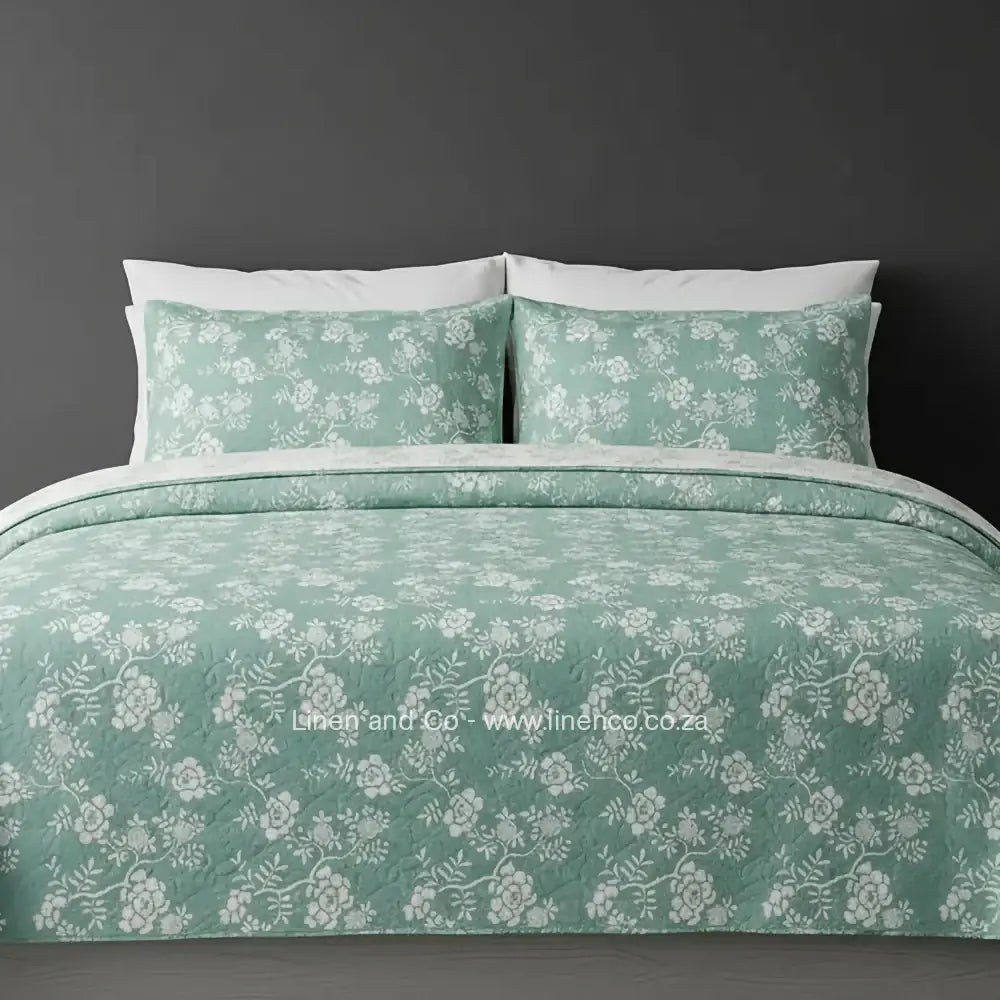 Linen and Co Marine Rochelle Bedspread Set with delicate floral pattern, showcasing quilted comforter and matching pillow cases on a bed against a dark background, highlighting sophisticated hospitality textile design