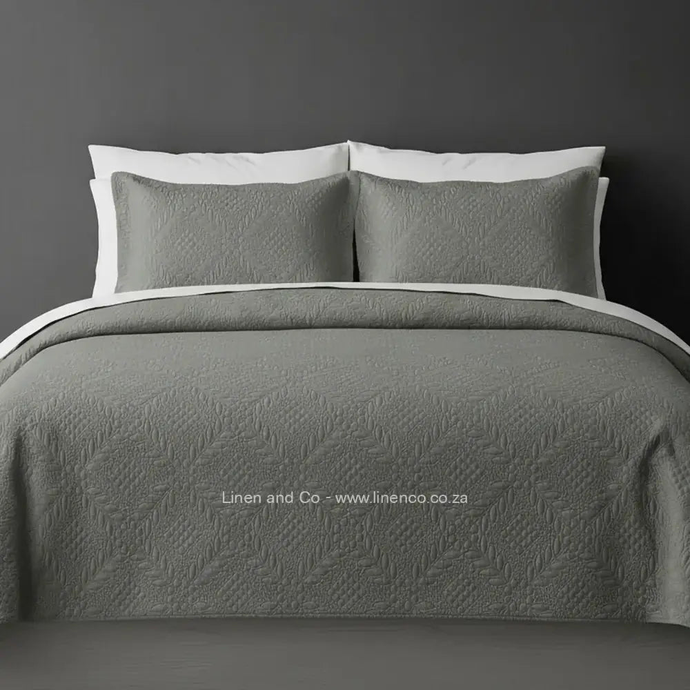 Platinum Quilted Bedspread Set with Istanbul Design, showcasing textured comforter and matching pillow cases on a bed against a dark grey wall, highlighting professional hospitality textile styling by Linen and Co