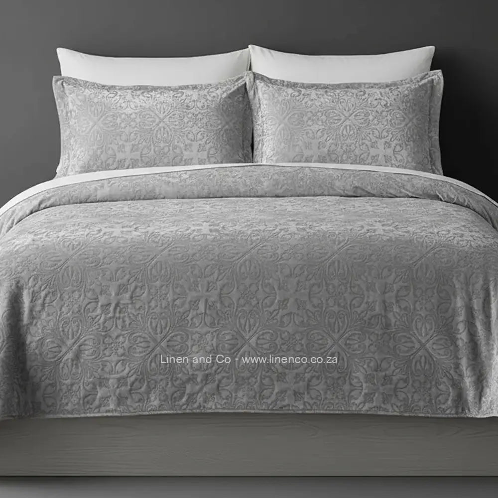 Grey Quilted Bedspread Set with French Velvet, showcasing textured comforter and matching pillow cases on a bed against a dark grey wall, highlighting professional hospitality textile styling by Linen and Co.