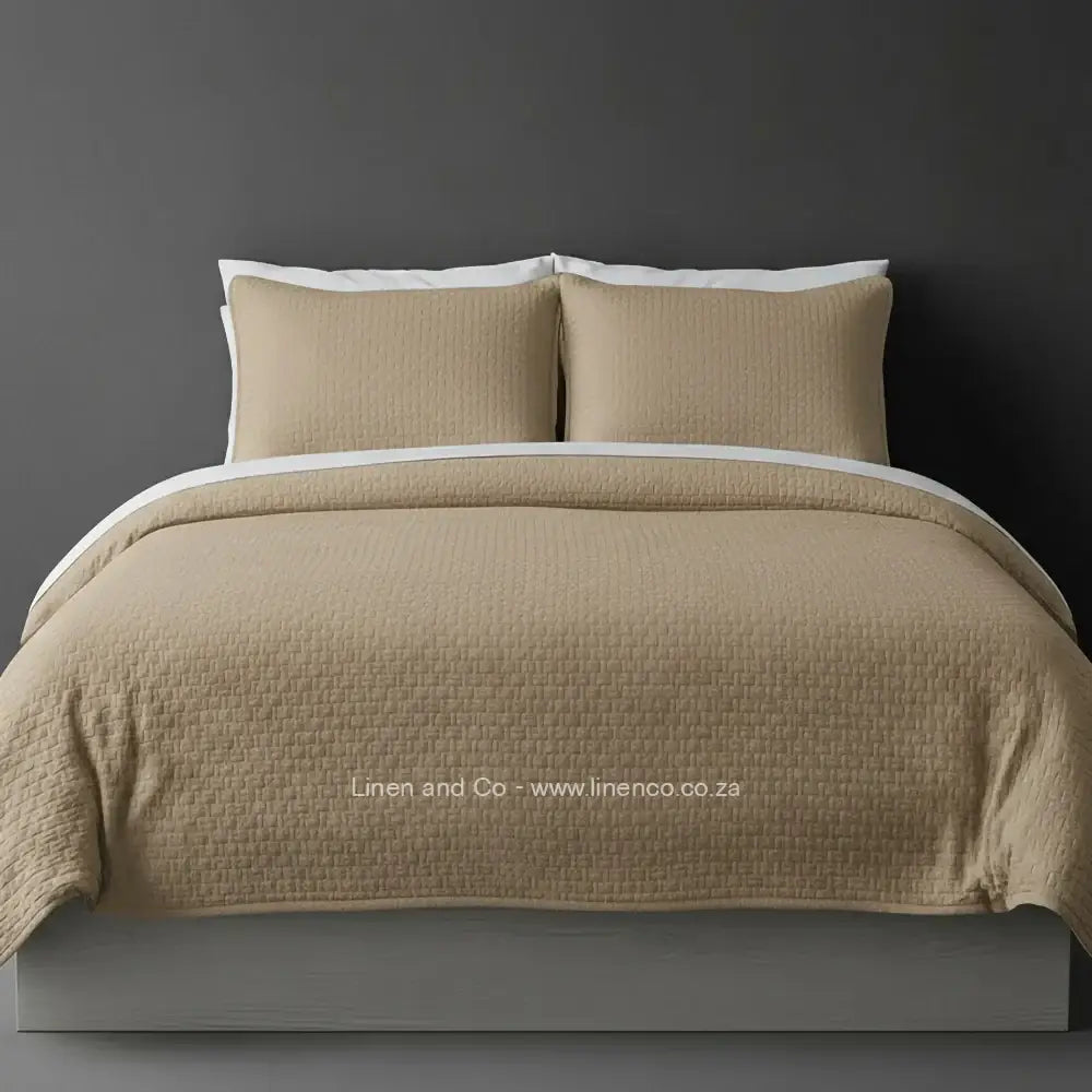 Stone Quilted Bedspread Set with Berlin Design, showcasing textured comforter and matching pillow cases on a bed against a dark grey wall, highlighting professional hospitality textile styling by Linen and Co.