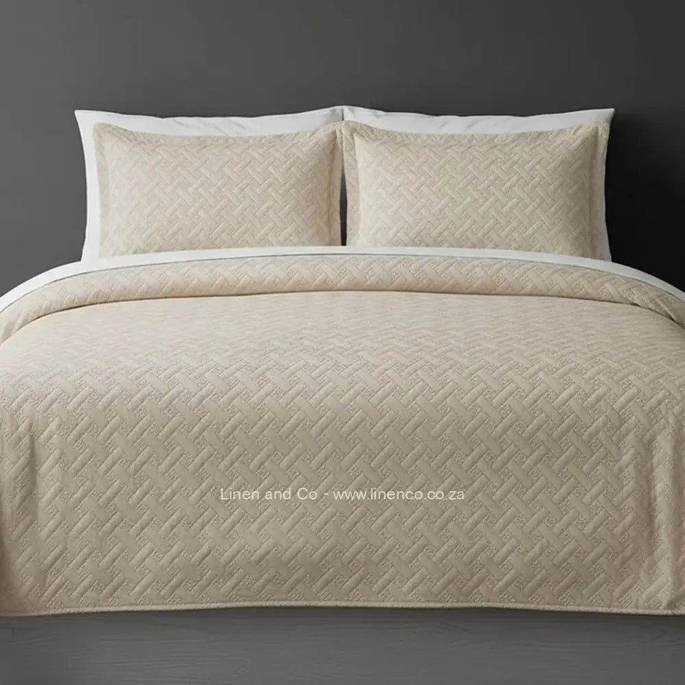 Beige Quilted Bedspread Set with Italian Velvet, showcasing textured comforter and matching pillow cases on a bed against a dark grey wall, highlighting professional hospitality textile styling by Linen and Co.