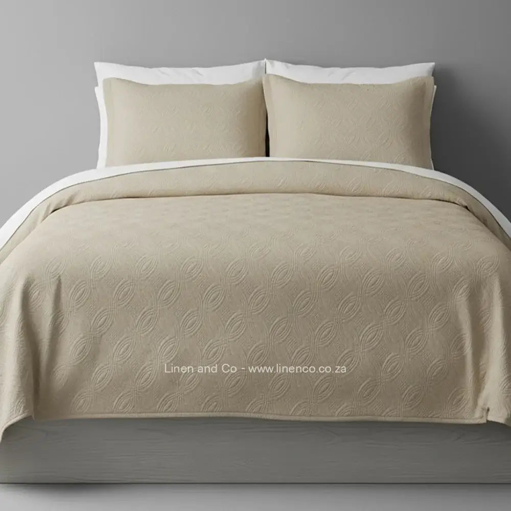Stone Quilted Bedspread Set with Munich Design, showcasing textured comforter and matching pillow cases on a bed against a dark grey wall, highlighting professional hospitality textile styling by Linen and Co.