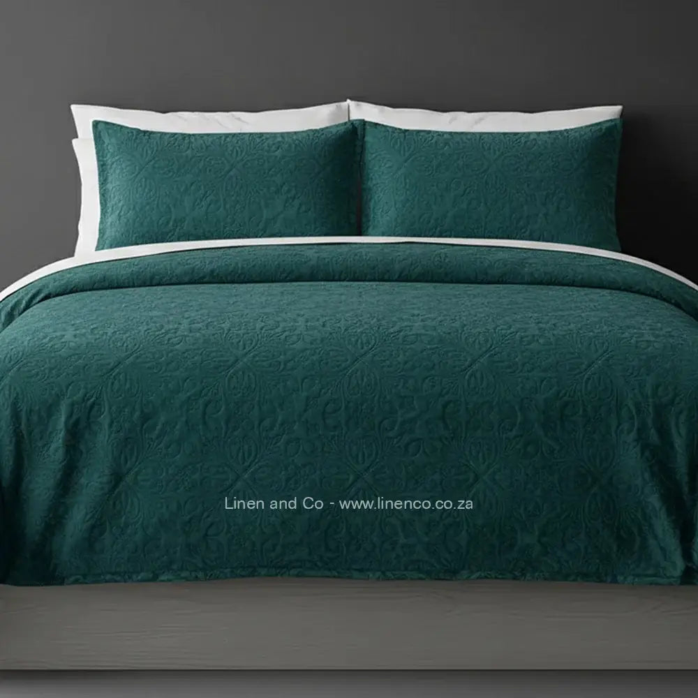 Teal Quilted Bedspread Set with French Velvet, showcasing textured comforter and matching pillow cases on a bed against a dark grey wall, highlighting professional hospitality textile styling by Linen and Co.