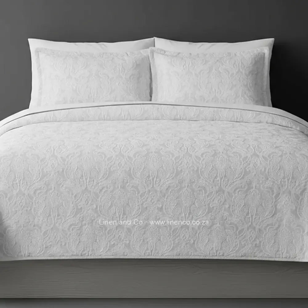 Linen and Co White Kensington Jacquard Bedspread Set with intricate textured pattern, showcasing quilted comforter and matching pillows against a dark background, highlighting sophisticated hospitality textile design