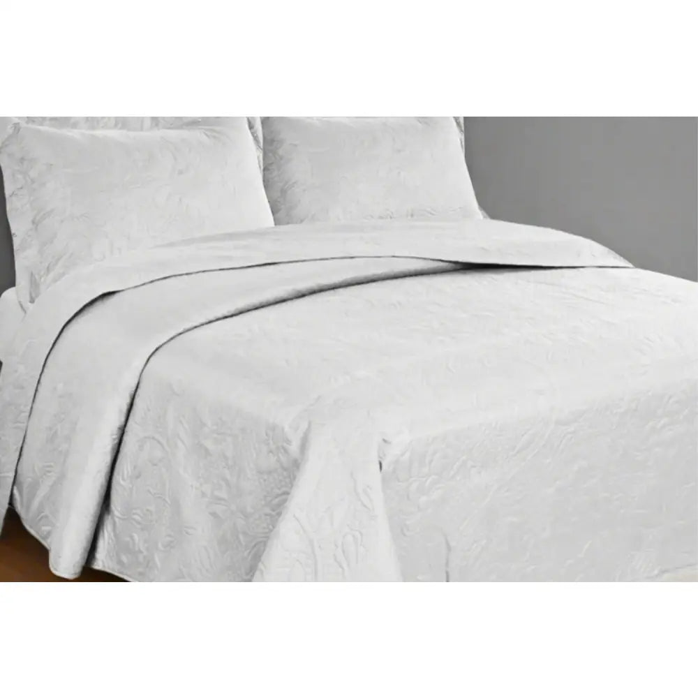 White Carmen Design textured bedspread on a bed with matching pillows in a bedroom setting.