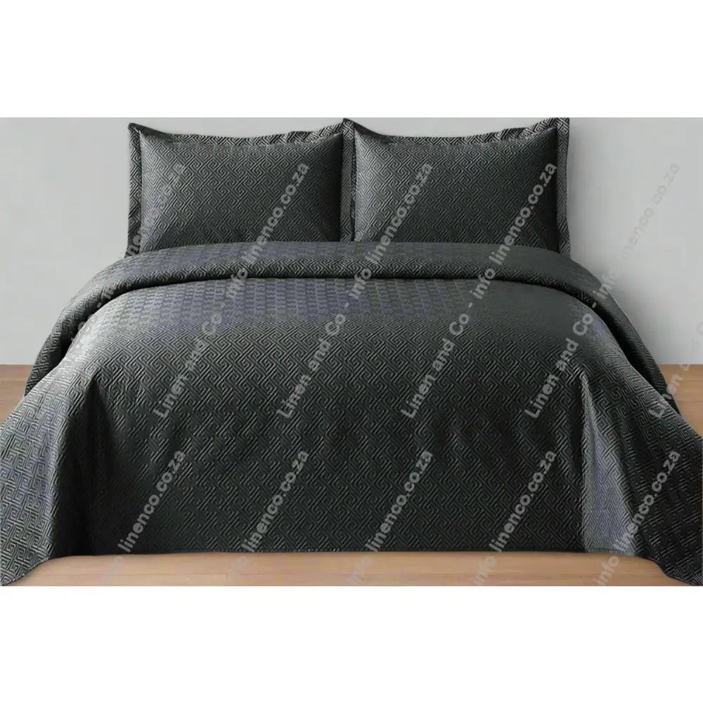 Charcoal Grey Rome Design Quilted Bedspread set on a bed.