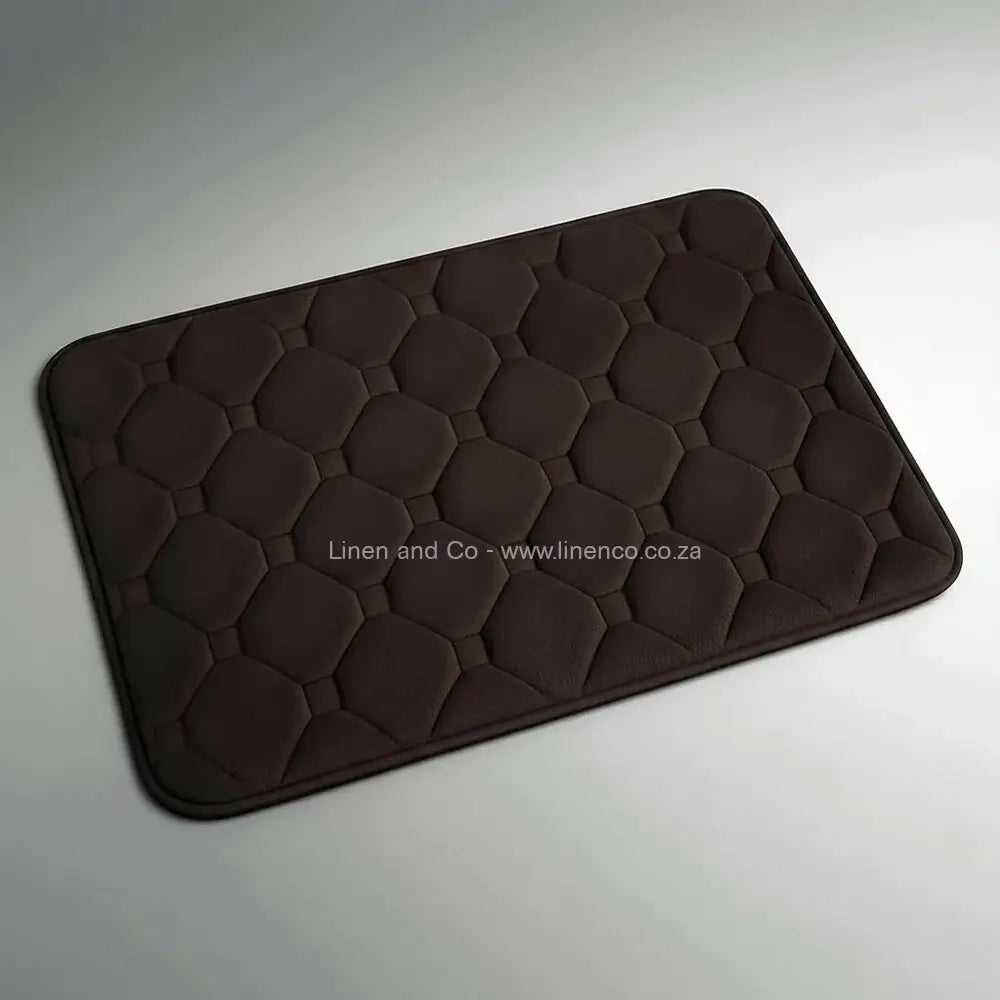 Chocolate memory foam bath mat by Linen & Co on soft grey gradient background, 50x80cm luxury microfibre bathroom accessory with non-slip backing