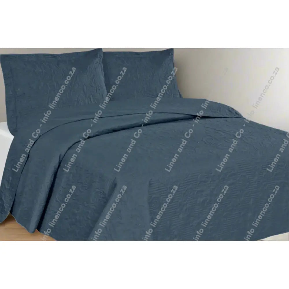 Denim Melissa Design textured quilt and pillow set on a bed in a bedroom setting.