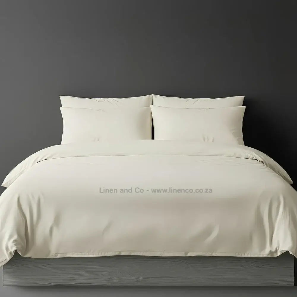 Cream percale duvet cover set from Linen and Co, showcasing pristine white bedding against a dark grey background, demonstrating clean and professional hospitality textile design