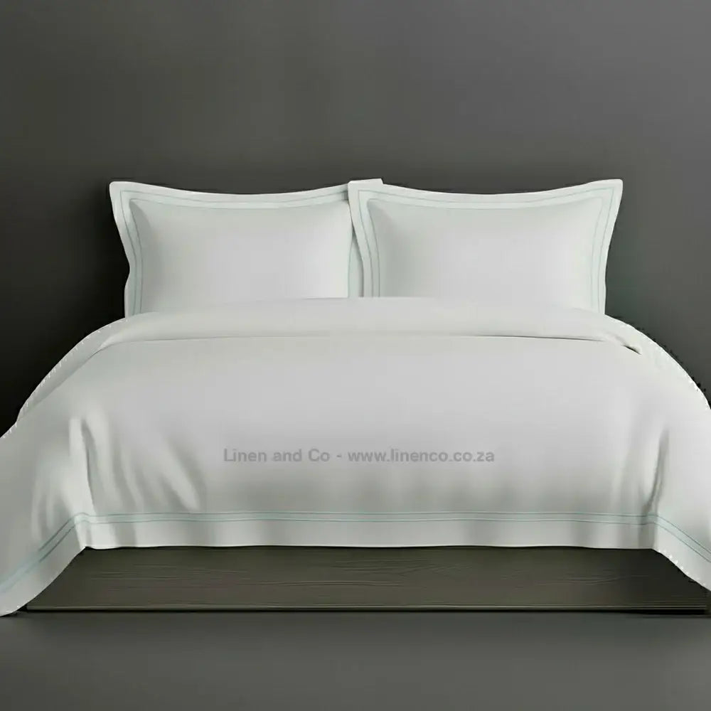 White percale duvet cover set with Oxford two-row white satin stitch border from Linen and Co, showcasing elegant hospitality bedding with subtle decorative detailing against a dark grey background.