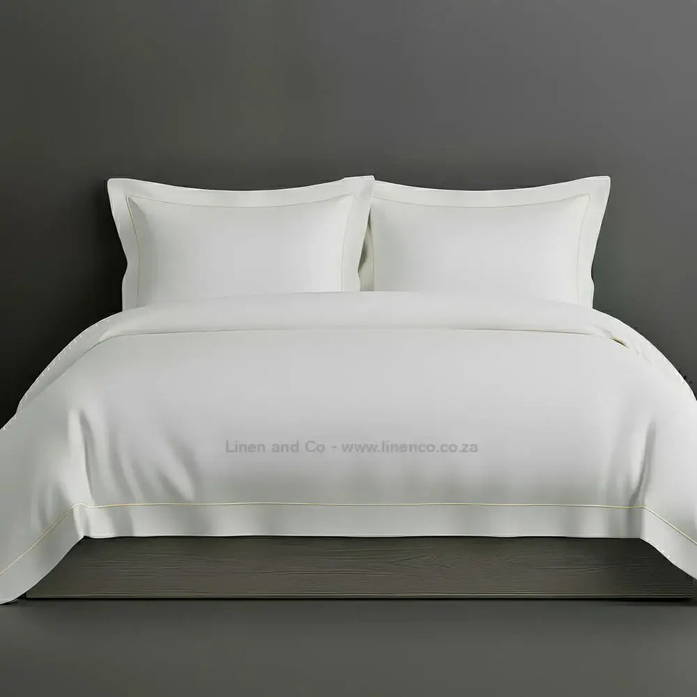 White percale duvet cover set with Oxford two-row white satin stitch border from Linen and Co, showcasing elegant hospitality bedding with subtle decorative detailing against a dark grey background.