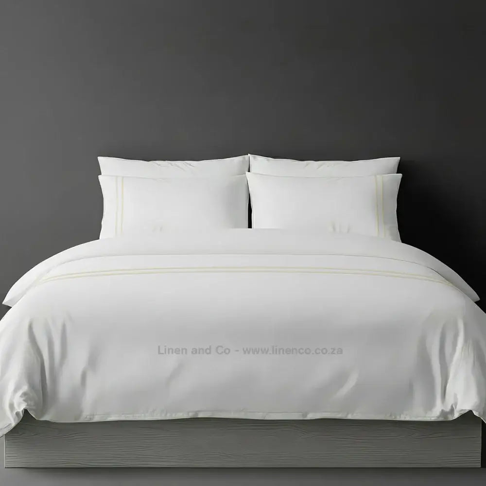 White percale duvet cover set with two-row white satin stitch border from Linen and Co, showcasing elegant hospitality bedding with subtle decorative detailing against a dark grey background