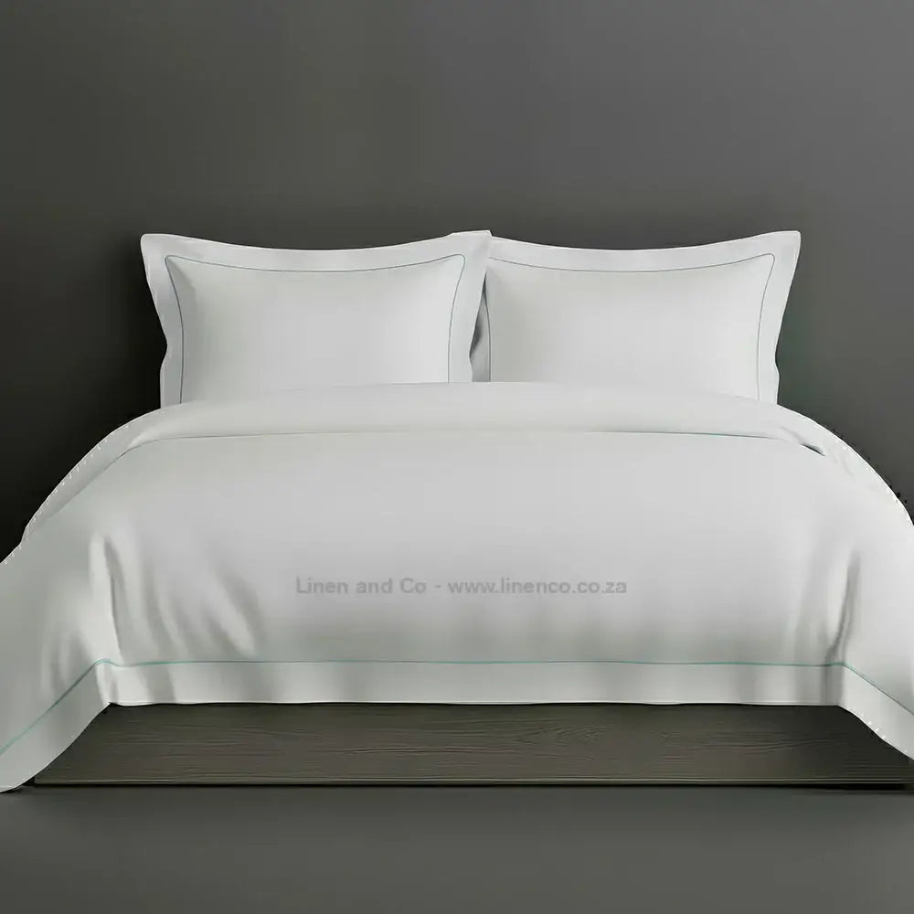 White percale duvet cover set with Oxford two-row white satin stitch border from Linen and Co, showcasing elegant hospitality bedding with subtle decorative detailing against a dark grey background.