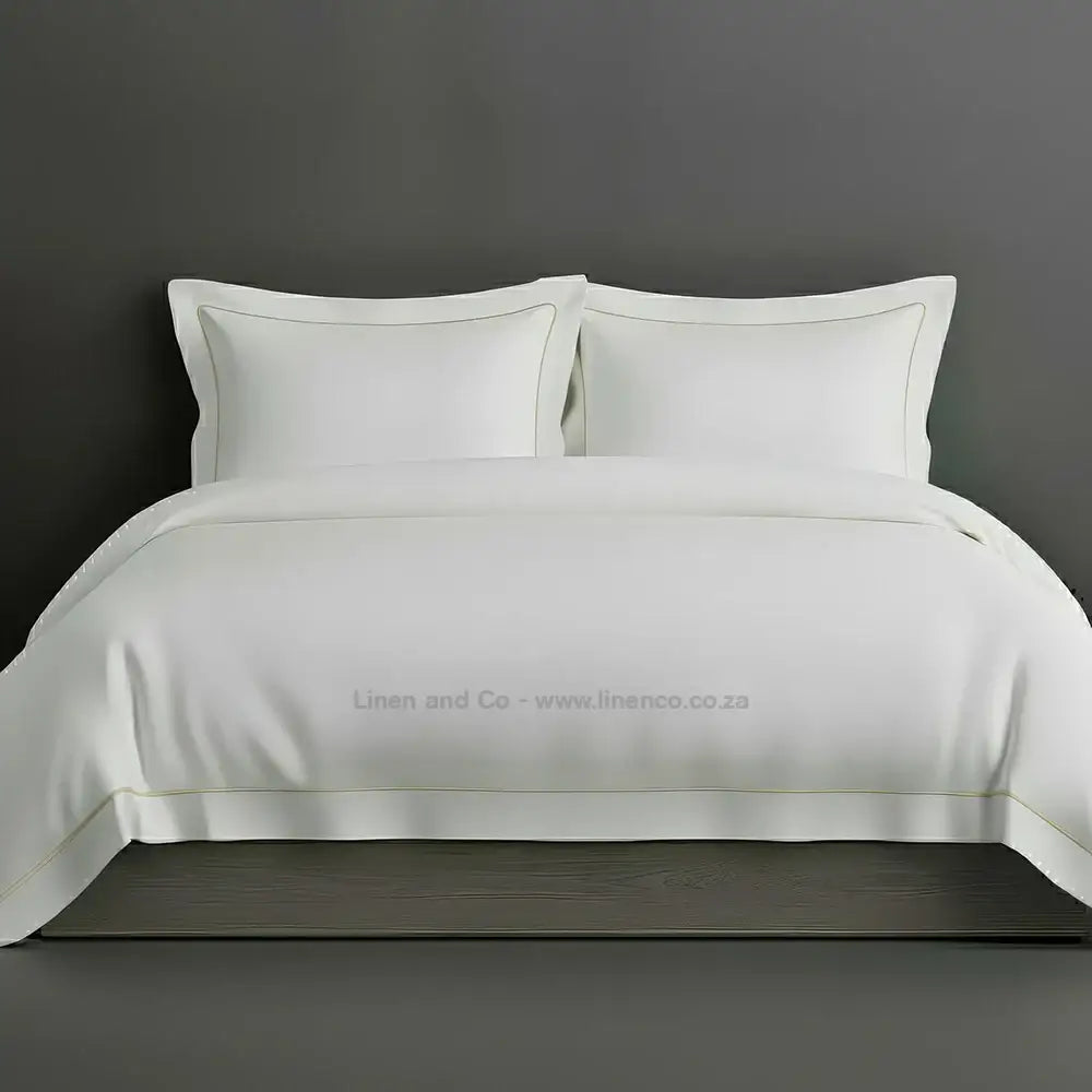 White percale duvet cover set with Oxford two-row white satin stitch border from Linen and Co, showcasing elegant hospitality bedding with subtle decorative detailing against a dark grey background.