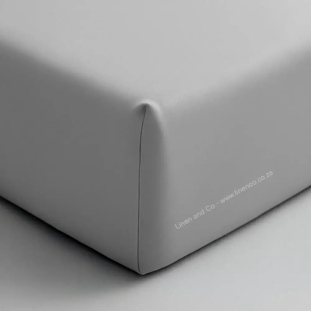 Grey fitted sheet corner on mattress showing elastic edge and smooth percale fabric - Linen & Co hospitality bedding